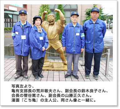 写真左より、亀有支部長の荒井敏夫さん、副会長の鈴木良子さん、会長の菅谷篤さん、副会長の山勝正久さん。漫画『こち亀』の主人公、両さん像と一緒に。